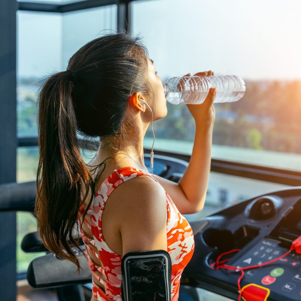Young woman drinking water in the gym. Exercise concept.